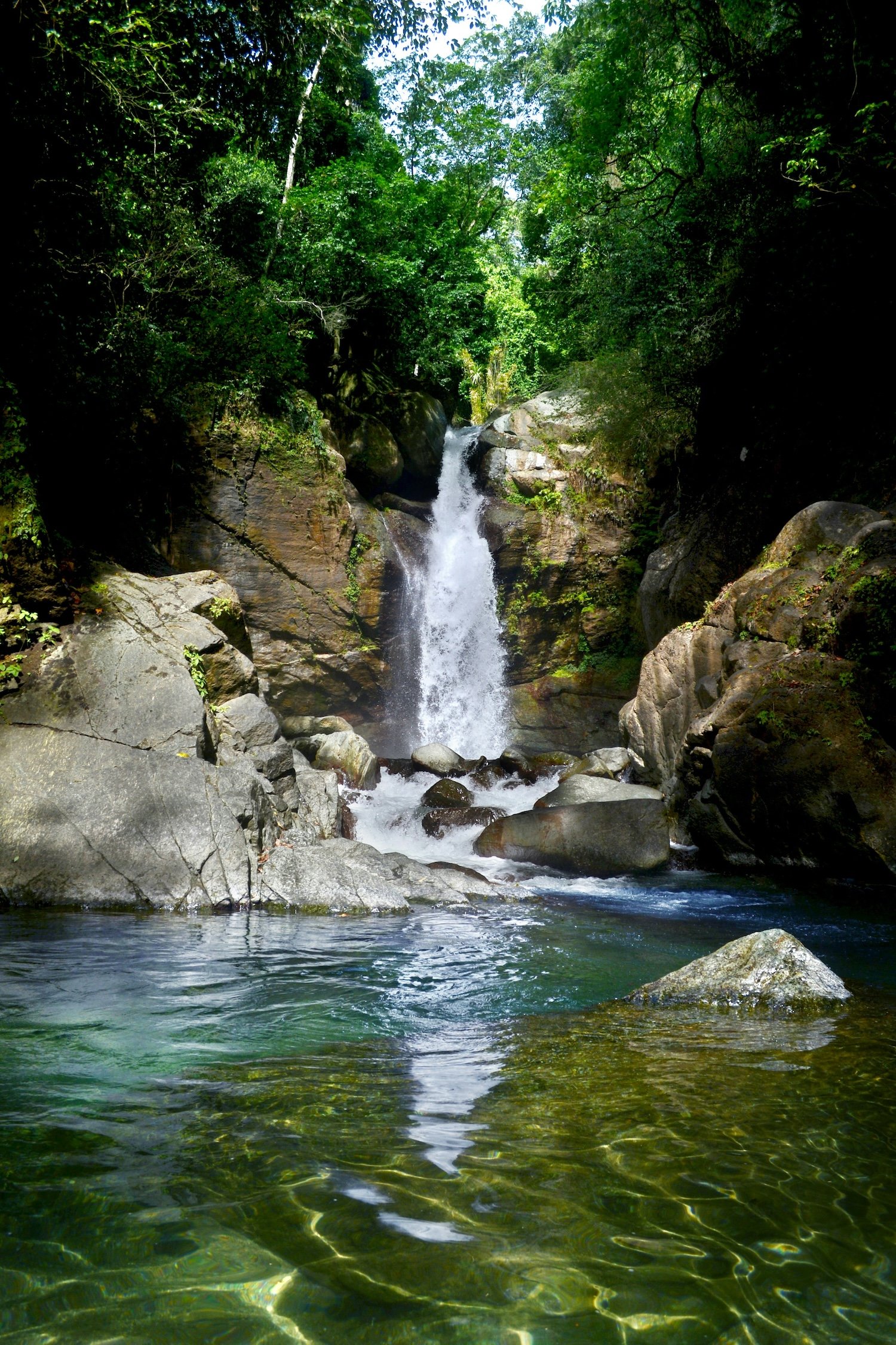 Waterfall cascading over rocks into a clear jungle pool