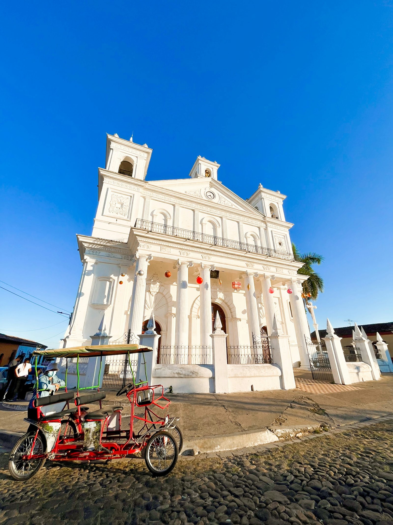 The white Iglesia Santa Lucía in Suchitoto with a pedicab on the cobblestones, El Salvador