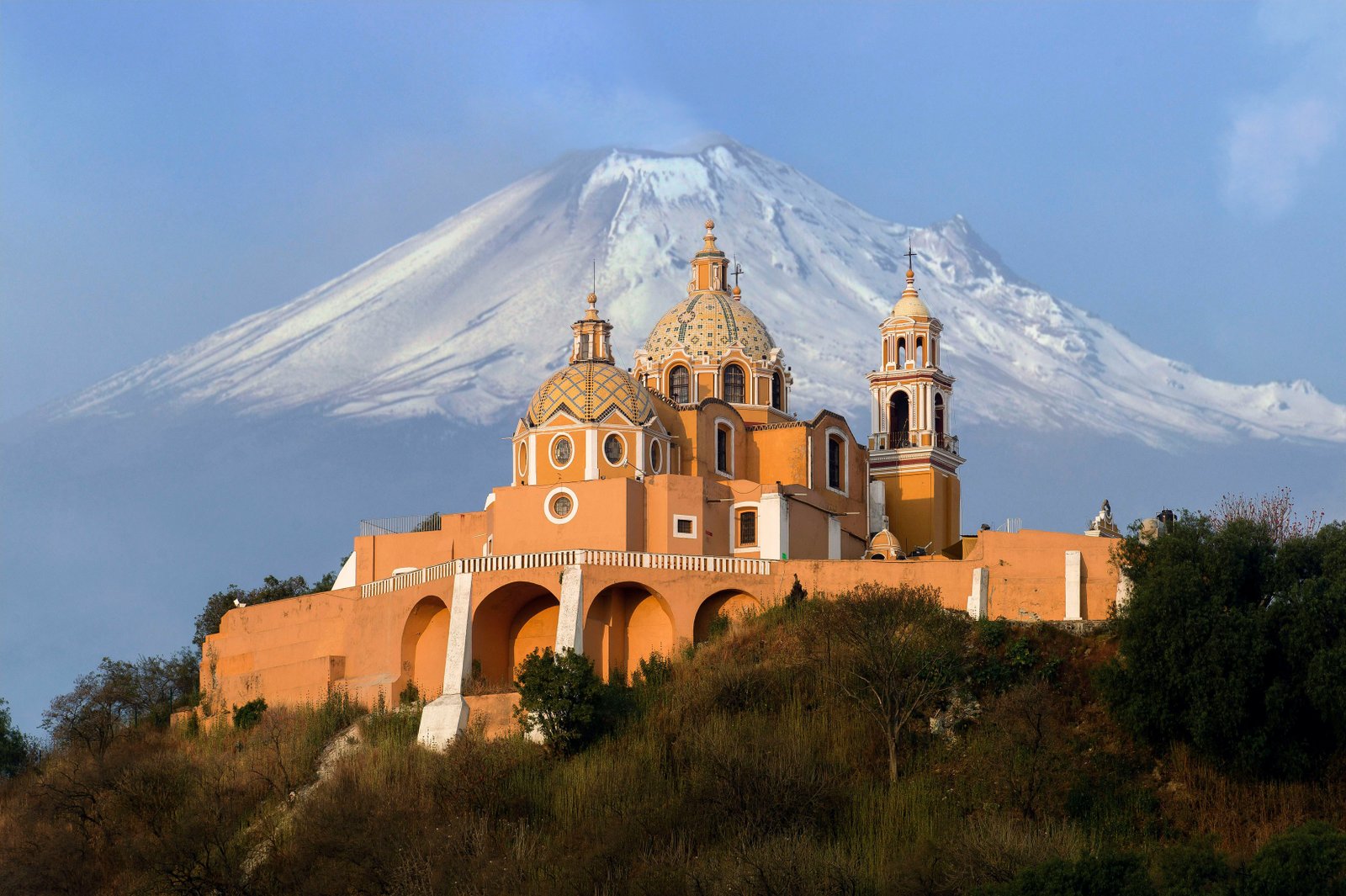 Cholula church in Puebla with the snow-capped Popocatépetl volcano rising behind it